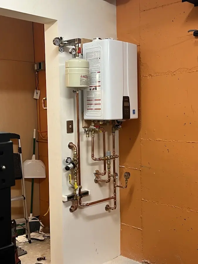 Plumbing technician inspecting water heater connections in Chesaning